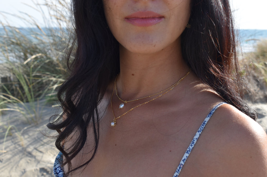 Model with beach as background - Layering of gold necklaces - Rice pearl necklace - Vermeil and Gold Plated jewelry - Piper and Pearl - Dainty handmade jewelry made in Montreal - Freshwater pearls